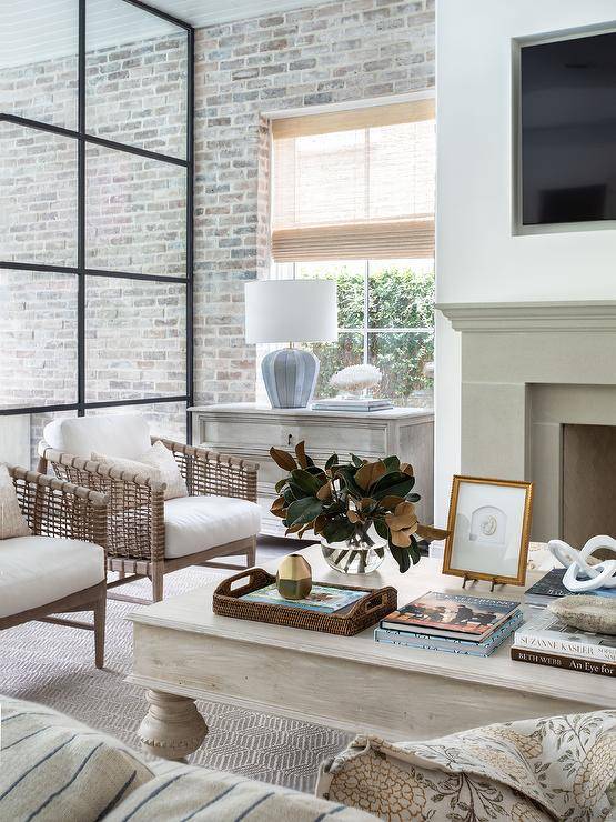 Welcoming living room features beige rope and wood accent chairs placed at a whitewashed French coffee table positioned on a beige rug.