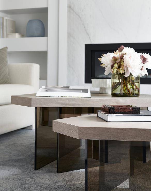 Wood and glass geometric coffee tables sit on a gray rug in front of a white sofa.