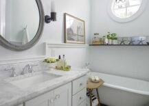 Amazing beachy cottage bathroom with vintage clawfoot tub, charcoal gray slate tiles, pale gray single bathroom cabinet vanity with marble countertop, glass knobs, pale blue walls paint color, gray vintage mirror, oil-rubbed bronze sconces and starfish.