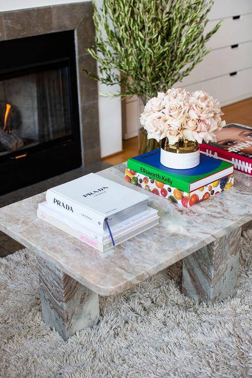 A pink and gray marble coffee table sits on a gray shag rug in a gorgeous closet sitting area, with flowers and books arranged on top