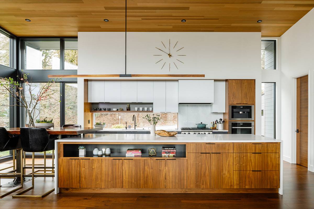 A mid-century modern kitchen with white cabinets, built-in storage within the island, and dark wood accents.