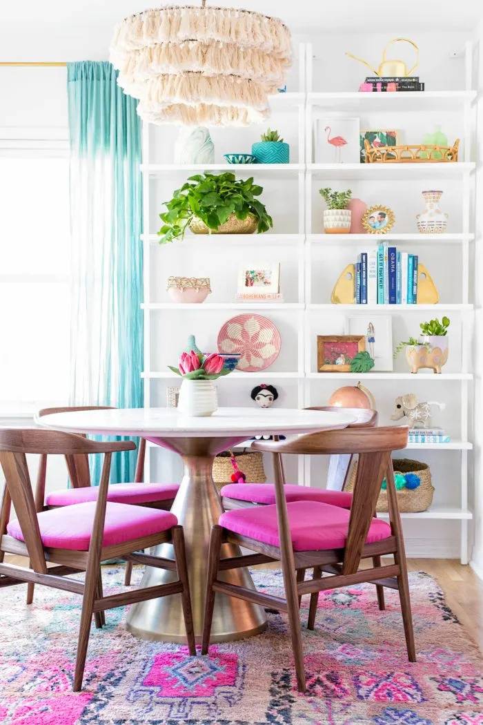 A dining area with colorful shelves and a pink rug