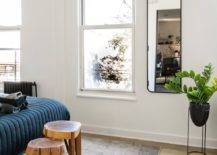 open studio apartment with rug two wooden stools white walls black frame mirror