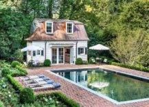 White cottage style pool house is accented with a copper roof.