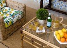 Placed on a seagrass rug, a woven chair with charming lemon print cushions is placed at a bamboo coffee table with a glass top.