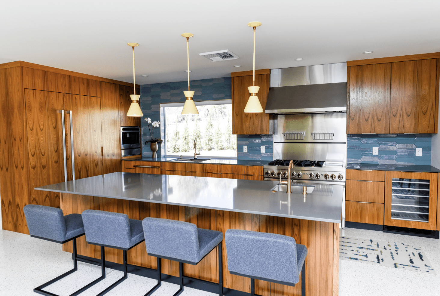 Dark cabinetry mid century modern kitchen with wood finishes, navy blue chairs, and navy blue accents.