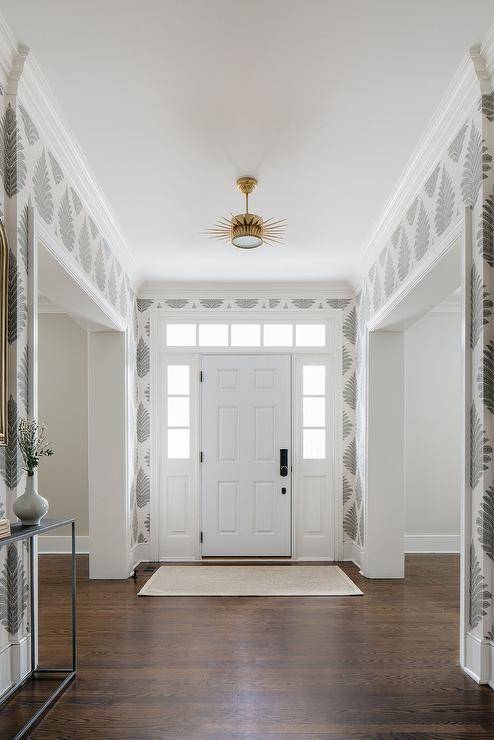 Spacious foyer features a Suzanne Kasler Soleil small semi-flush, white and gray block print wallpaper and a white door.