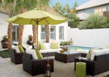 Relax poolside beneath a lime green umbrella accenting a lime green stool table and lime green pillows placed atop dark brown wicker chairs and facing dark brown wicker sofas finished with white seat cushion. The seating area is centered around a dark brown wicker coffee table placed on a gray shag rug.