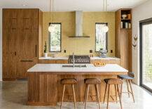 large mid century modern kitchen with teak wood cabinetry with yellow backsplash.