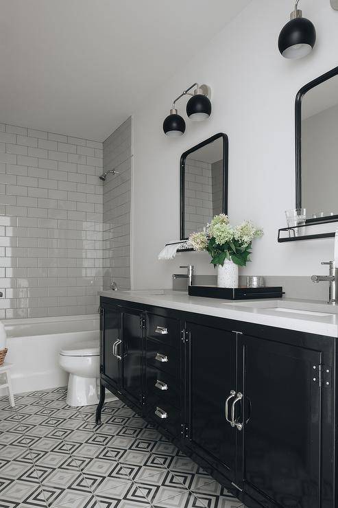 Restoration Hardware Pharmacy Double Vanity featuring a light gray quartz countertop, chrome fauces and a black mirror with a shelf. Gray and black diamond pattern floor tiles bring a charming finish to the surface of the bathroom.