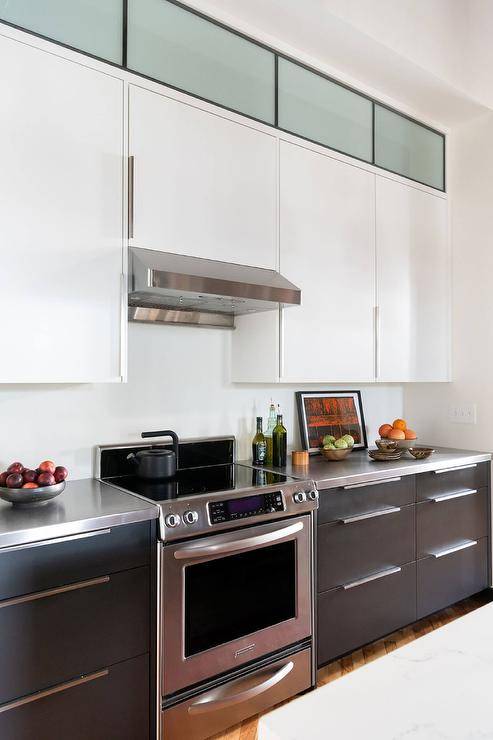 Kitchen features black and white flat front cabinetry with stainless steel countertops.