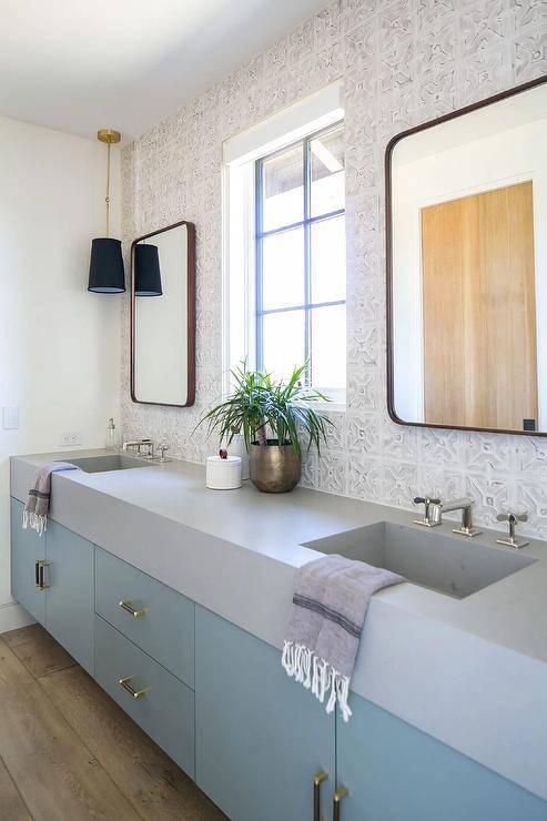 Bathroom features curved brass mirrors mounted on whitewashed vintage tiles over a sky blue double bath vanity that boasts brass pulls, topped with gray quartz.