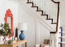 Eclectic entryway with full wall wainscoting framing an Asian style console table topped with a pagoda sculpture and a blue urchin lamp with a coral pink Baroque mirror above and a pair of stools upholstered in Chiang Mai Dragon - China Blue fabric below across from a French grain sack slipcovered chair.