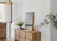 Entryway features a salvaged wood credenza on a white vertical plank wall and a gray rug that leads to a plank Dutch door.