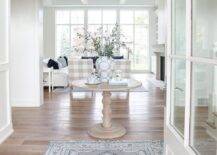 Large foyer features a blue and gray entry rug layered on white engineered oak floors, and leads to a round entryway accent table.