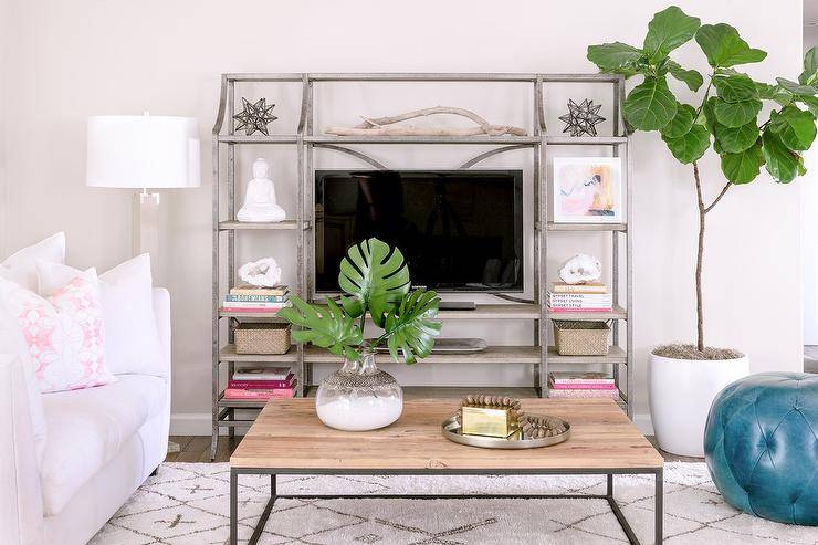 Metal and wood tv shelving unit flanked by a tall white lamp and a fiddle leaf fig display an industrial design in the most functional and practical design.