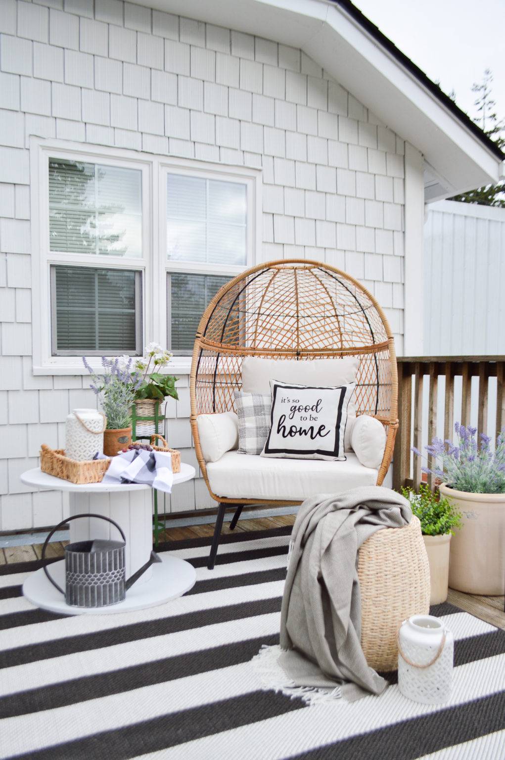 a relaxing outdoor area with a large chair and striped rug