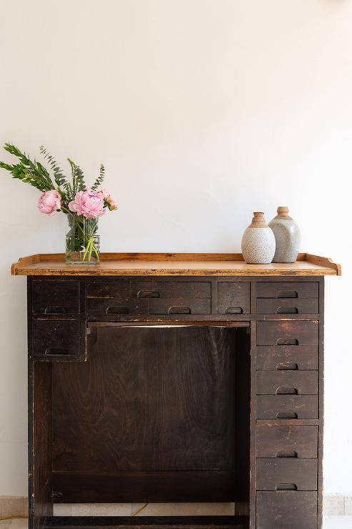 Workspace features vintage wooden desk with drawers.