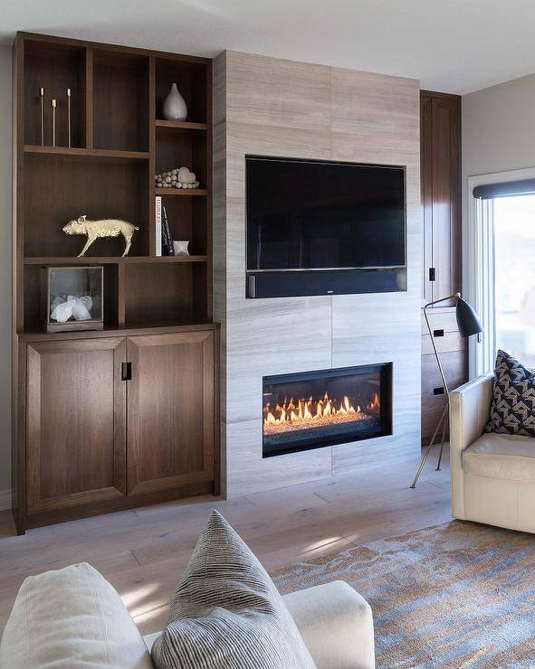 Gray stone fireplace with an inset tv flanked by brown oak built-in shelves in a transitional living room.