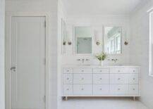Spacious bathroom features a modern white double washstand under white Parsons mirrors flanked by long sconces.