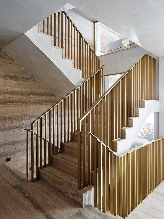 Modern brass staircase railing boasts brown steps.