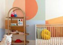 Color block walls accent a contemporary nursery boasting a vintage arched bookshelf placed beside a white and tan vintage crib.