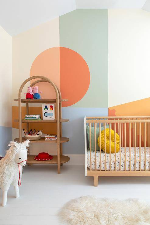 Color block walls accent a contemporary nursery boasting a vintage arched bookshelf placed beside a white and tan vintage crib.