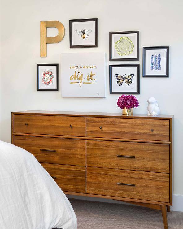 Mid-century modern wooden dresser styled in a kids bedroom features an art gallery with personalized art.