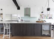 black kitchen island against white cabinets with aquamarine backsplash
