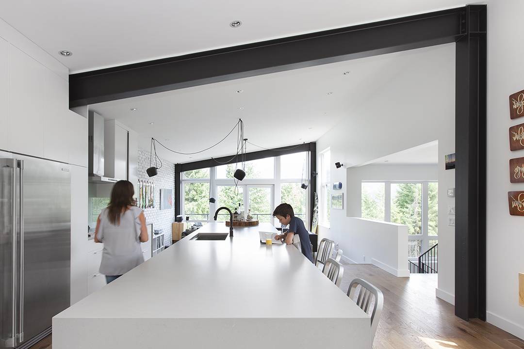 woman and child in modern white kitchen with black steel beam framing the room