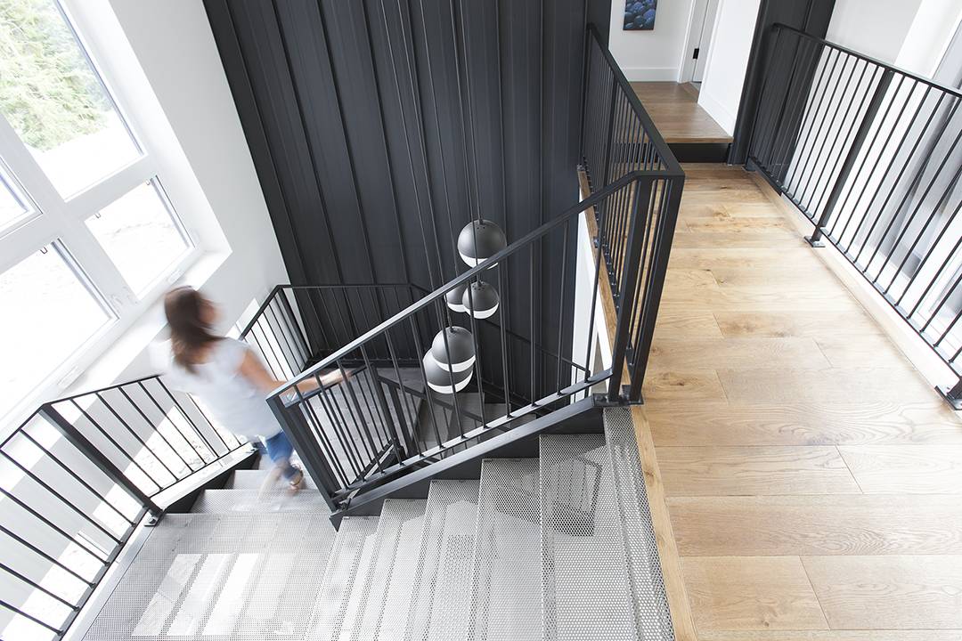 A woman descending modern industrial stairs leading from wood floor landing