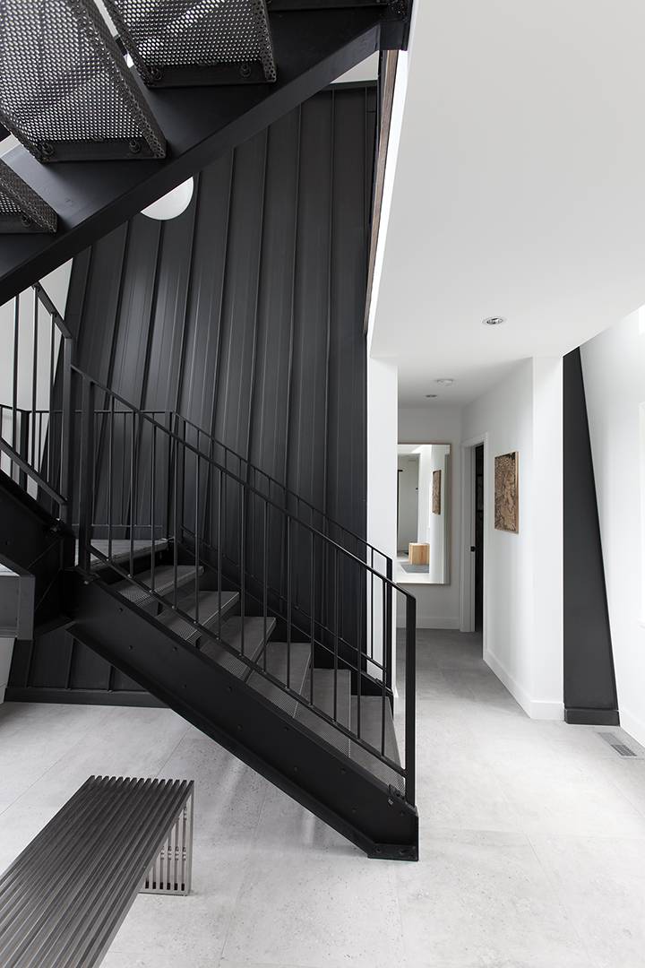 white main floor entryway with black industrial staircase and black accent wall