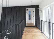 a hallway with a wooden floor and black walls.