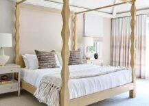 Bedroom features a gold carved wood canopy bed with brown woven pillows flanked by white wooden nighstands lit by white and gold lamps.