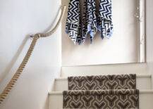 Cottage home features stairwell with rope railing and steps covered in gray and black geometric stair runner as well as towel hooks located at the top of the stairs.