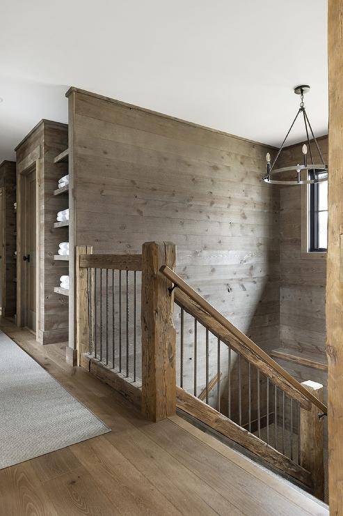 Country staircase features rustic wooden posts, a gold railing and brown oak plank walls.
