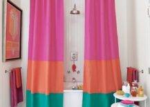 Amazing shower curtain is constructed by stitching together three fabrics in jewel tones. Color blocked shower curtain is made with fabrics by Grayline Fabrics ( Top to bottom: Fuchsia #37, Orange #28, and Aqua #55). Pair of colorful grommet shower curtains attached to ceiling mounted shower rail surround oval bathtub with rain shower head and beadboard backsplash. Spectacular bathroom features marble top nesting tables and Martha Stewart Towels in fun, bright shades.