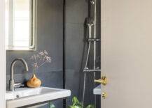 black bathroom with silver faucet, white sink and greenery
