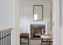 A bamboo mirror is mounted over an original fireplace with black marble surround with brown leather bench.