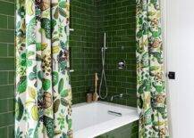 A green subway tiled drop-in bathtub is covered with 2 white and green shower curtains and fitted with a white quartz deck fixed against glossy green surround tiles.
