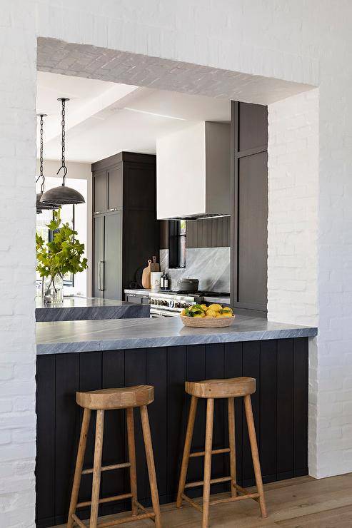 Modern kitchen features a dark brown plank breakfast bar with gray marble top and wooden tractor stools.