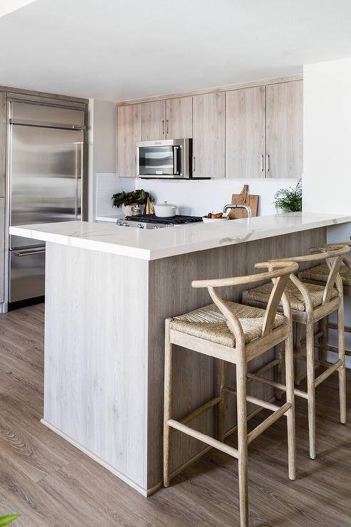 Kitchen features a brown kitchen peninsula breakfast bar with tan wishbone stools that boast abaca seats