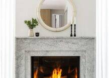 Bedroom features a round ivory shagreen mirror over a marble fireplace mantel.