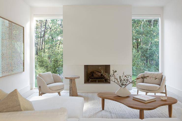 Modern living room features light gray boucle chairs with a vintage coffee table and modern fireplace.