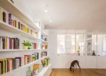 dog walking across wood floors of open living space with wall to wall book shelves