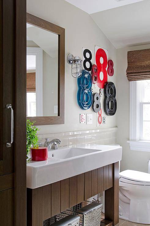 boy's bathroom features red, blue, and black number 8 art fixed over toilet beside a window and white porcelain sink with a stained oak vanity 