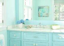 Turquoise kid's bathroom features a turquoise blue bath vanity topped with gray and white marble placed under a turquoise blue framed mirror illuminated by a Restoration Hardware Dillon Triple Sconce.