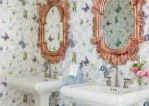 Harper Howey Interiors - Colorful shared girls' bathroom boasts pink baroque mirrors mounted on walls covered in Thibaut Butterfly Garden Wallpaper above two white pedestal washstands finished with satin nickel faucets. White hex floor tiles are covered in a purple, blue and green striped rug.