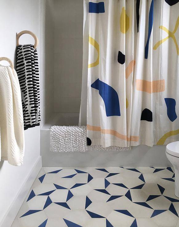 Light gray and blue bath floor tiles add a contemporary appeal to a kid's bathroom featuring a drop-in bathtub with a multi-colored shower curtain.