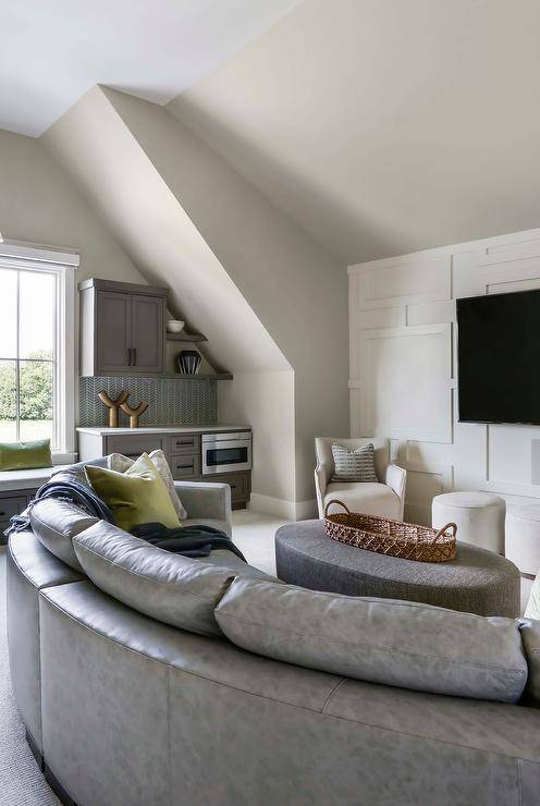 Sunken family room is styled with a gray curved leather sofa paired with a gray oval leather ottoman.